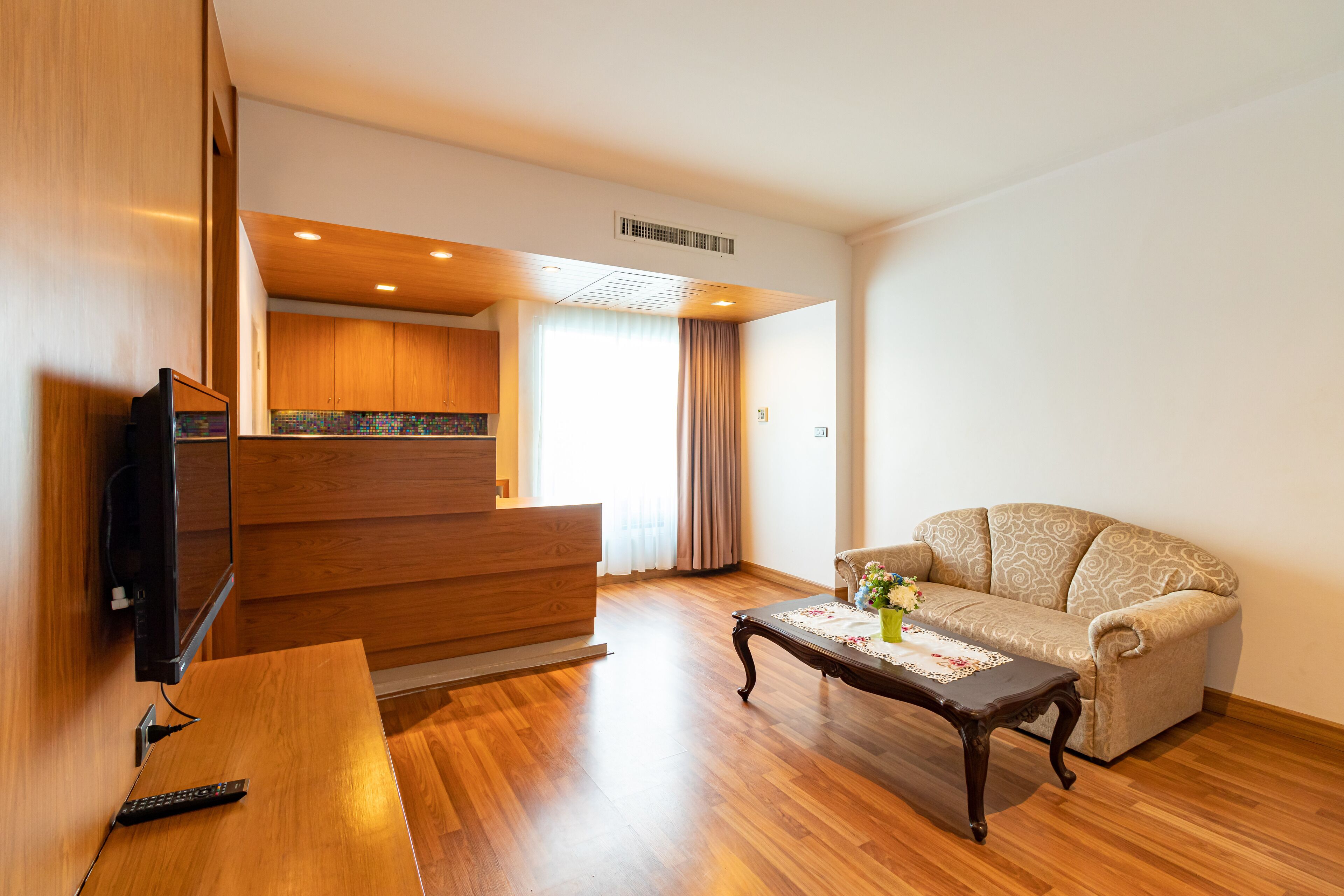A living room with a wooden floor, a sofa, a coffee table, and a TV.