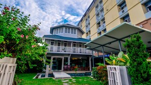 A hotel with a covered outdoor seating area, a pool, and a garden with flowers. - Viva Hotel Songkhla (Songkhla)