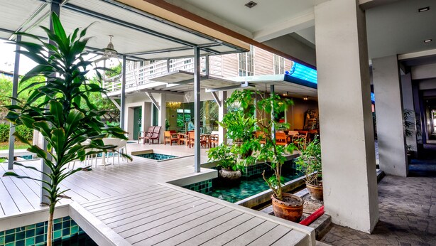 A spacious indoor pool area with multiple seating areas and potted plants. - Viva Hotel Songkhla (Songkhla)