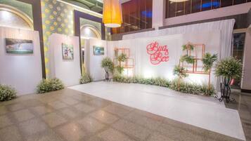 Uma área de recepção com fundo branco, um letreiro 'Luz Boa' e plantas em vasos.