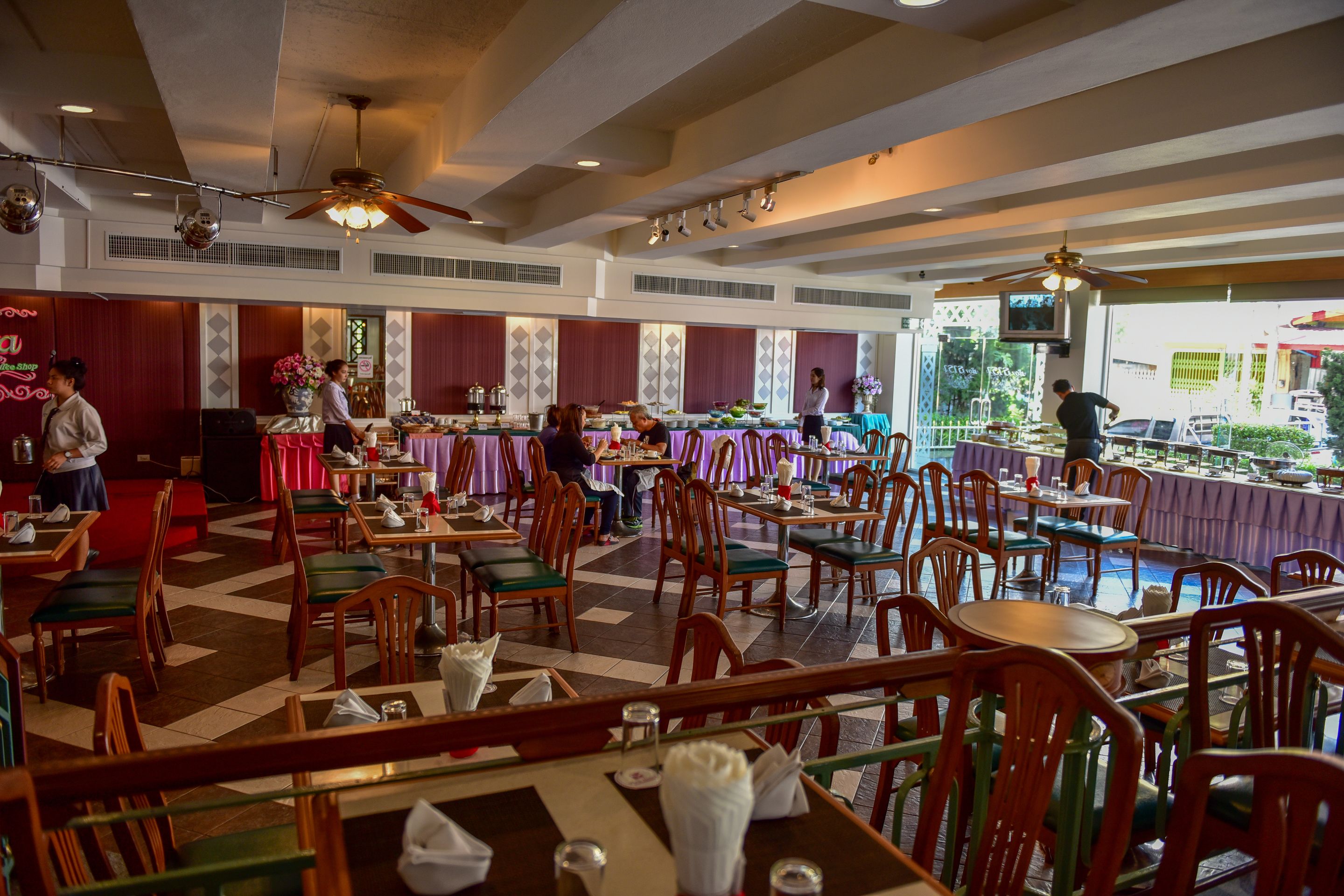 A spacious restaurant with high ceilings, multiple dining areas, and a view of the outside.