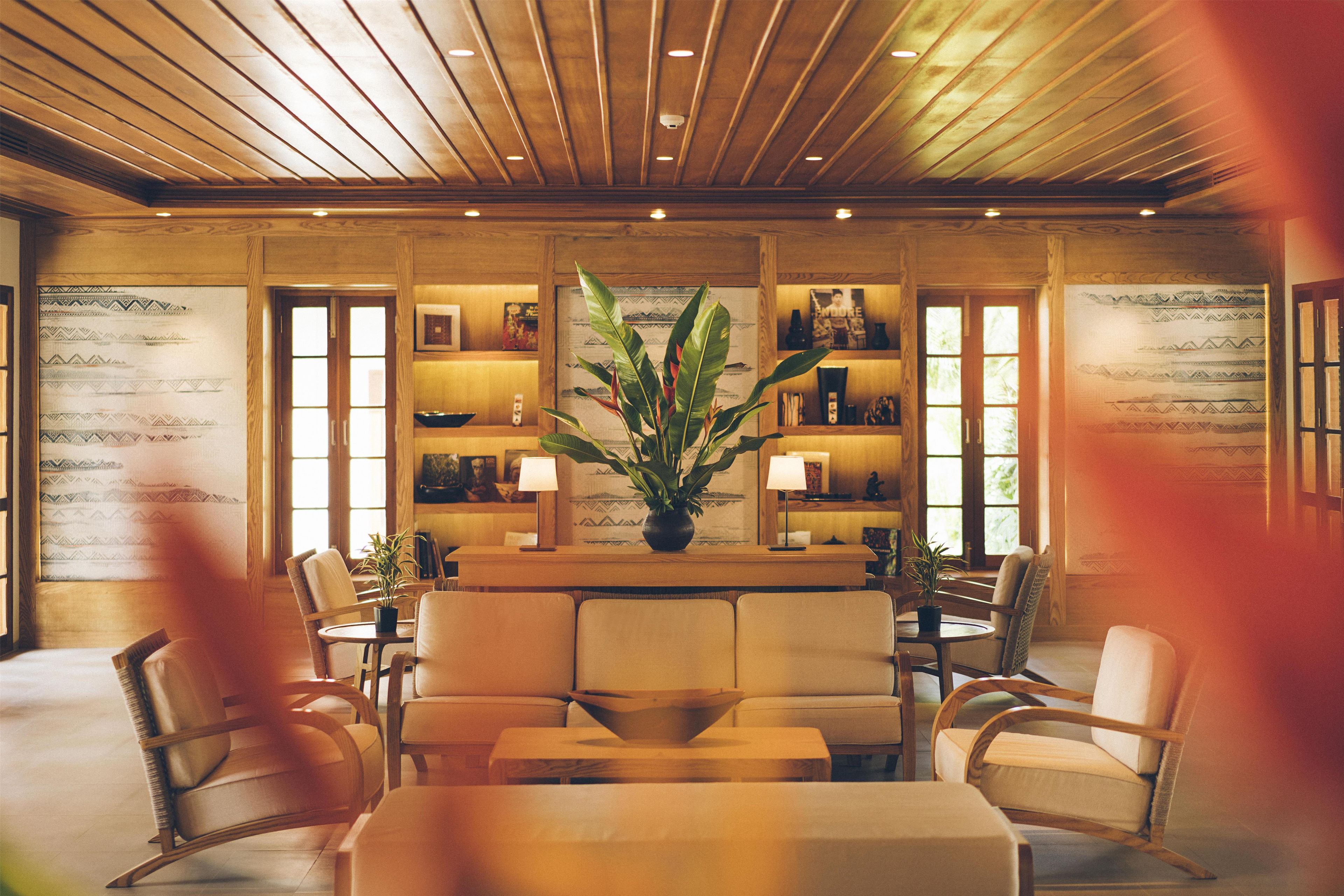 A room with a wooden ceiling, a central table with chairs, and shelves with decorative items.