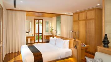 Quarto de hotel com cama grande, guarda-roupa de madeira, casa de banho com lavatório e espelho, e vista através de uma porta de vidro.