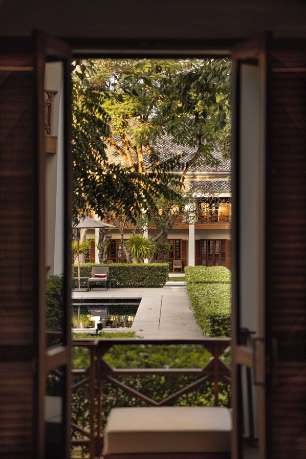 An open doorway leading to a courtyard with a bench, a table, and a chair.