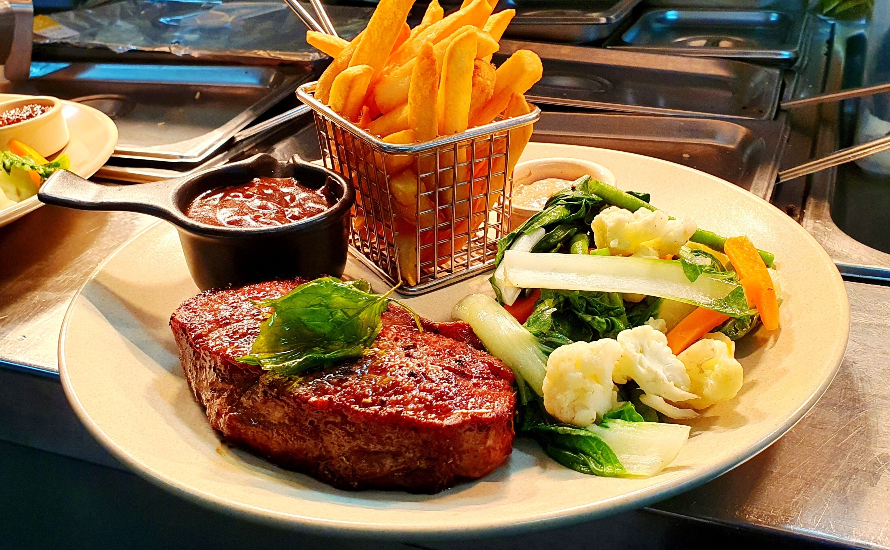 A plate with a steak, fries, and vegetables.