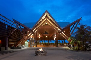 Un edificio moderno con una estructura de techo triangular, una chimenea central y zonas de estar al aire libre.