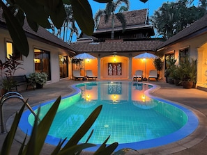 A pool area with a tiled floor, lounge chairs, and potted plants. - Coconut Paradise Holiday Villas (Rawai)