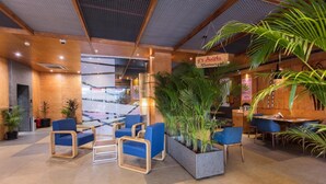 Un espace intérieur moderne, doté de coins salon, de plantes en pot et d’une enseigne de restaurant bien visible.