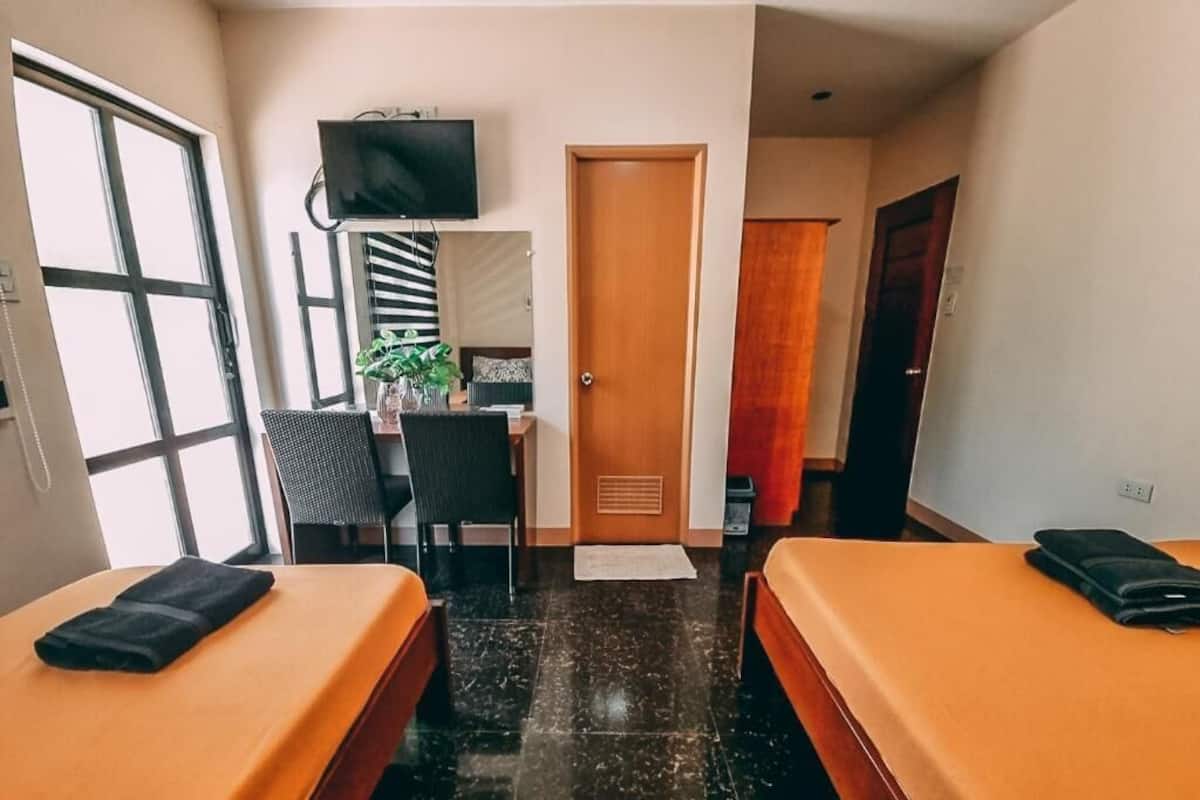 A hotel room with two beds, a TV, a desk, and a chair.