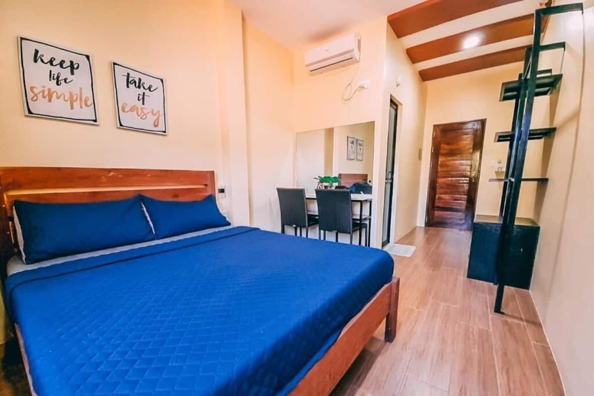 A bedroom with a bed, a desk, and a staircase.