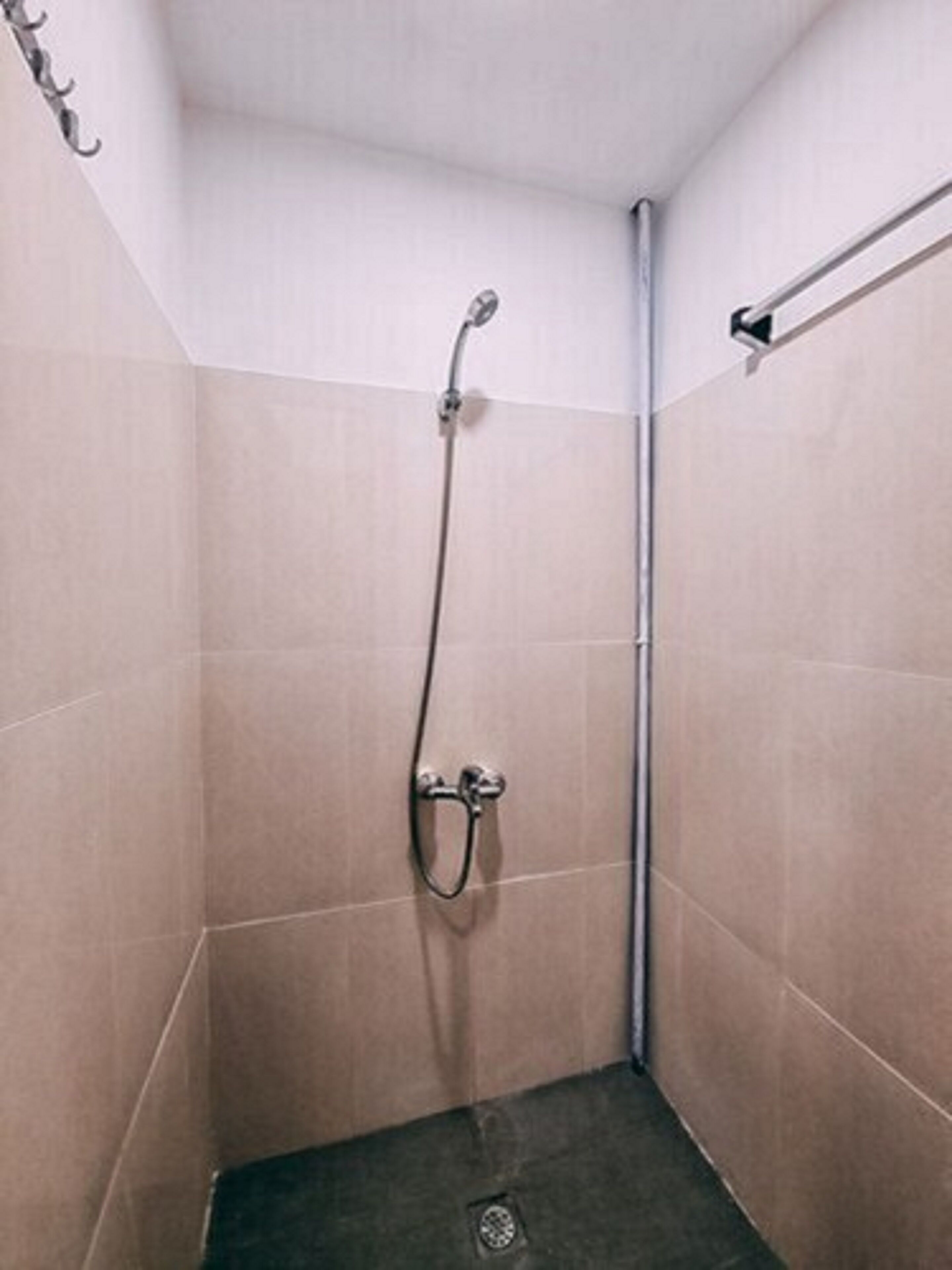 A small, enclosed shower area with a showerhead and a towel rack.