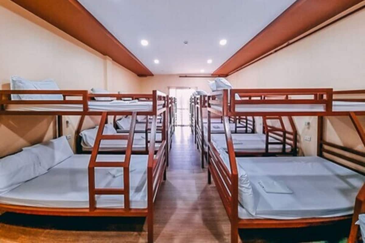 A room with bunk beds arranged in two rows, wooden walls, and a tiled floor.