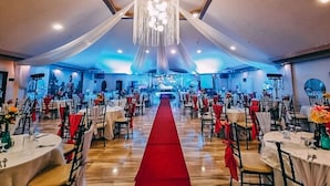 A banquet hall with round tables, a red carpet, and a chandelier. - Buddha Resort by Cocotel (Bugallon)