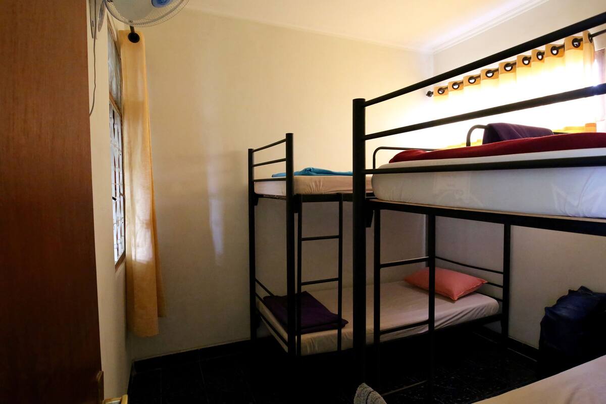 A bunk bed room with a window, a fan, and a door.
