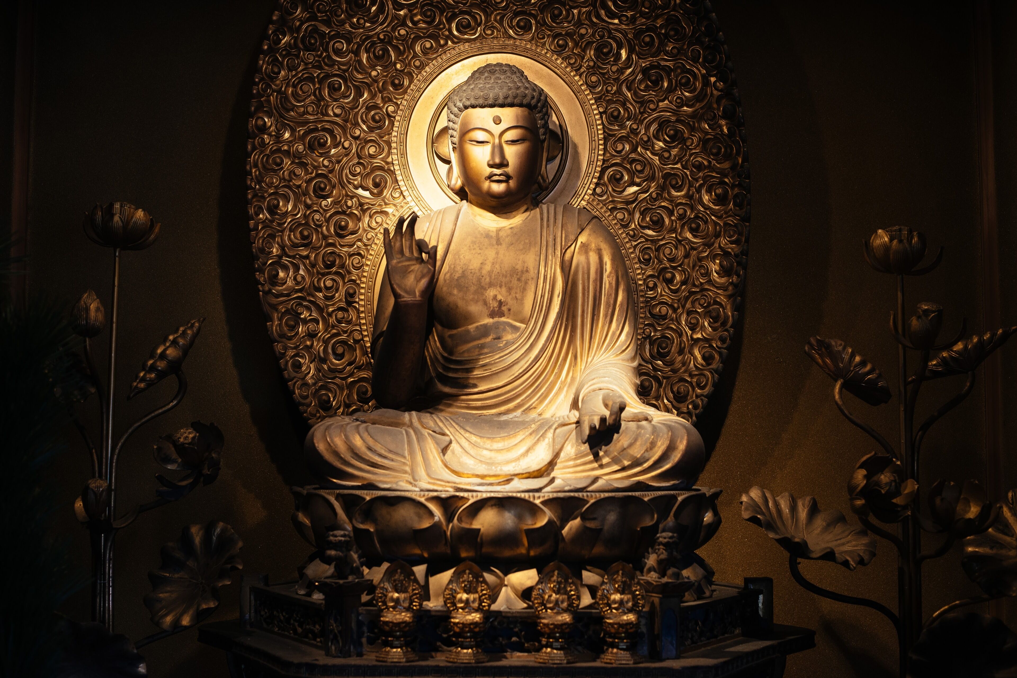 A large Buddha statue with intricate golden patterns and lotus decorations.