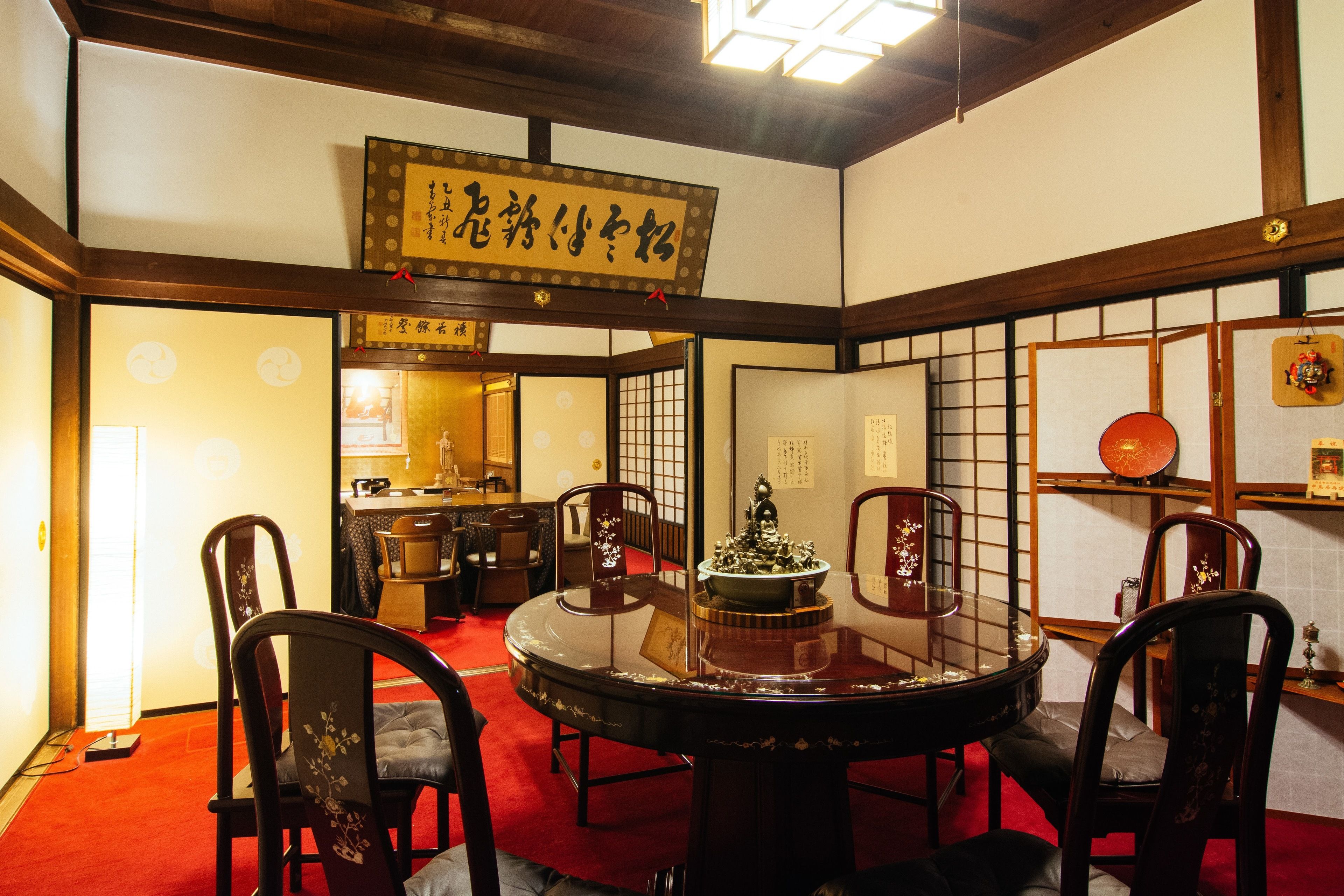 Una habitación japonesa tradicional con suelo de tatami, una mesa redonda con un centro decorativo y mobiliario de madera.