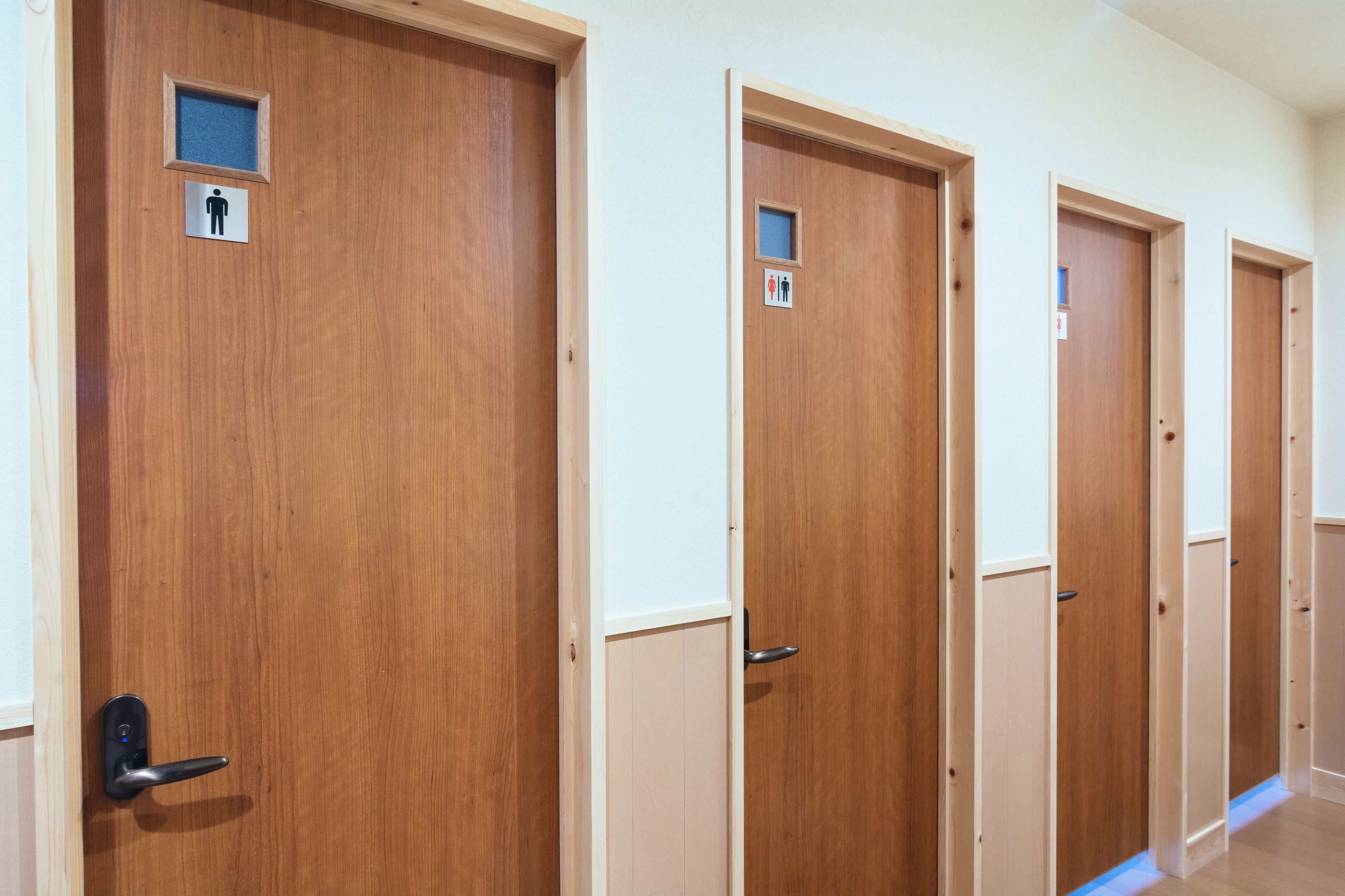 A row of wooden doors with gender-specific restroom signs.