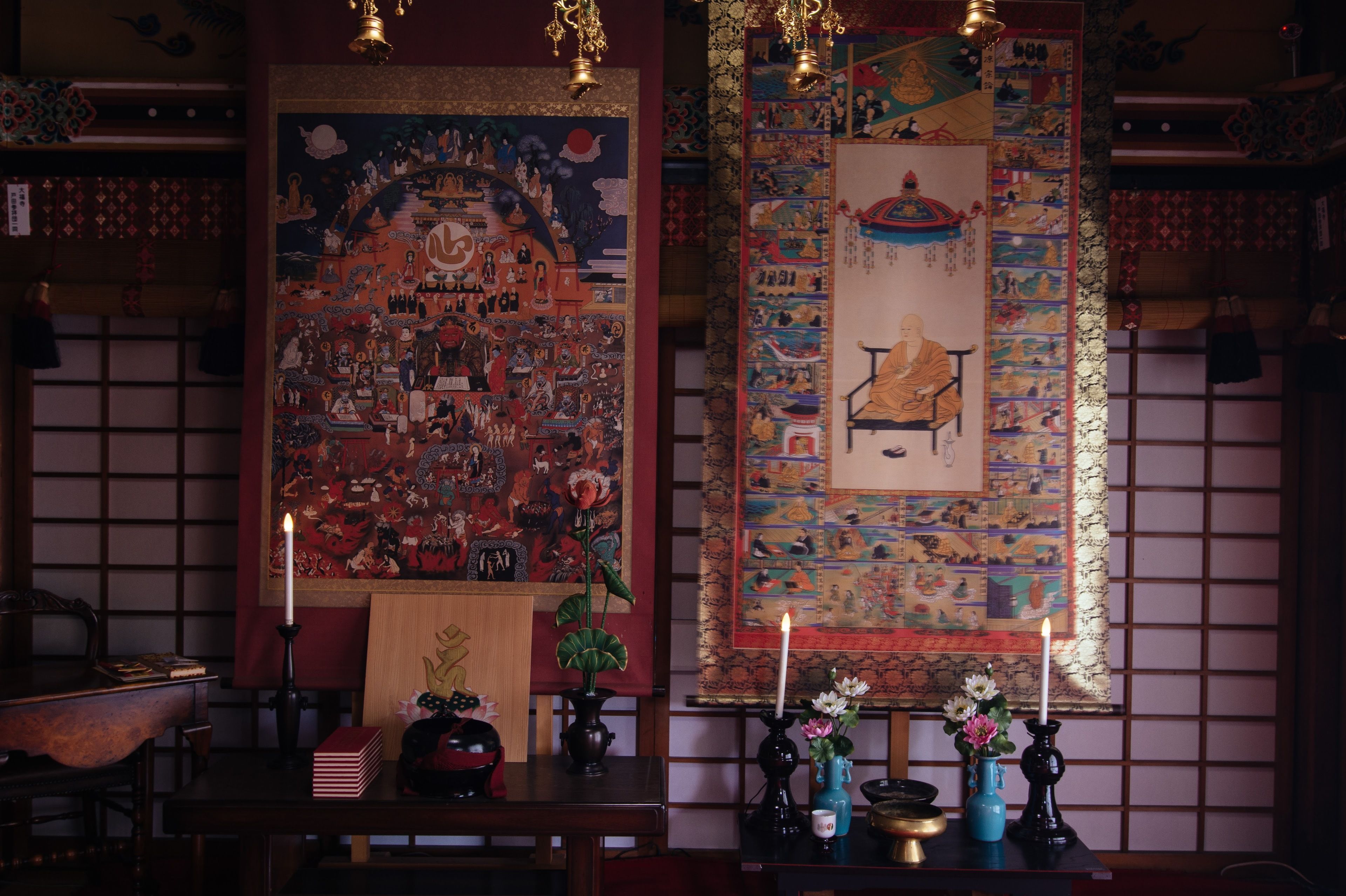 Una habitación tradicional con suelo de tatami, un escritorio de madera bajo y un pergamino colgado con ilustraciones detalladas.