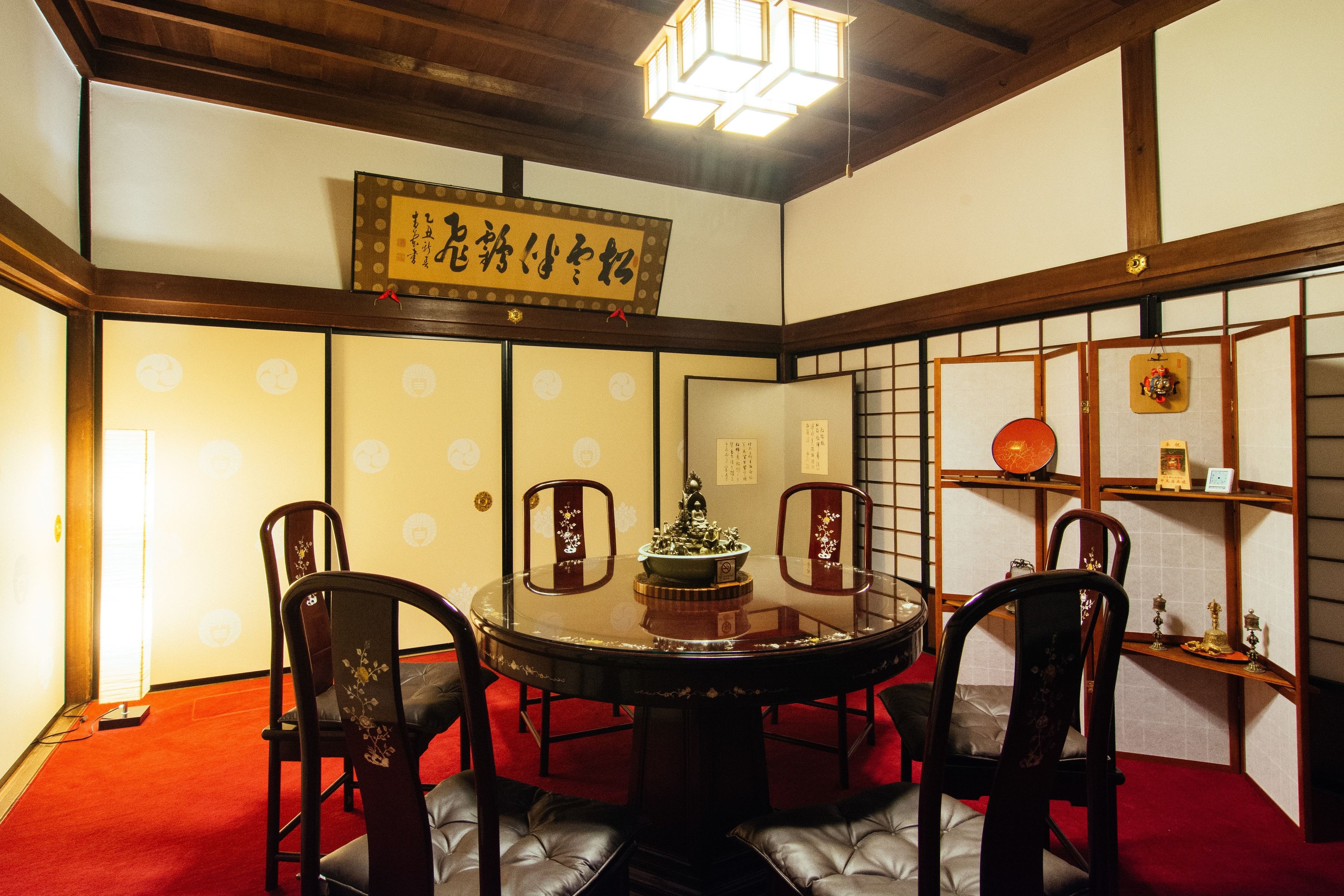 Una habitación tradicional japonesa con suelo de tatami, una mesa redonda con sillas y un panel shoji.