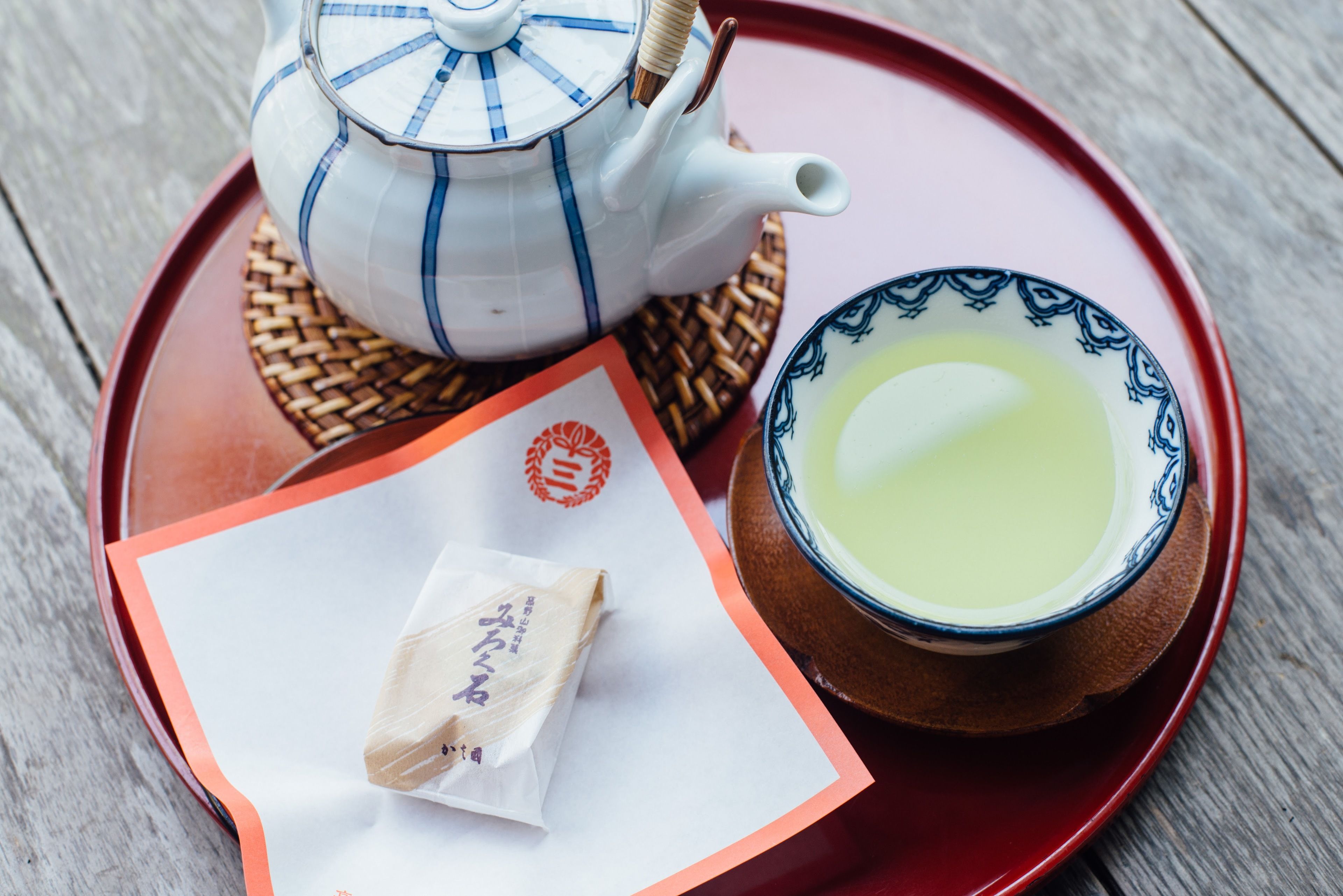 A teapot, a cup of tea, and a tea bag on a tray.