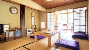 A traditional Japanese room with tatami flooring, a wooden table, purple cushions, sliding doors, and a television. - Koyasan Syukubo Kumagaiji (Koya)