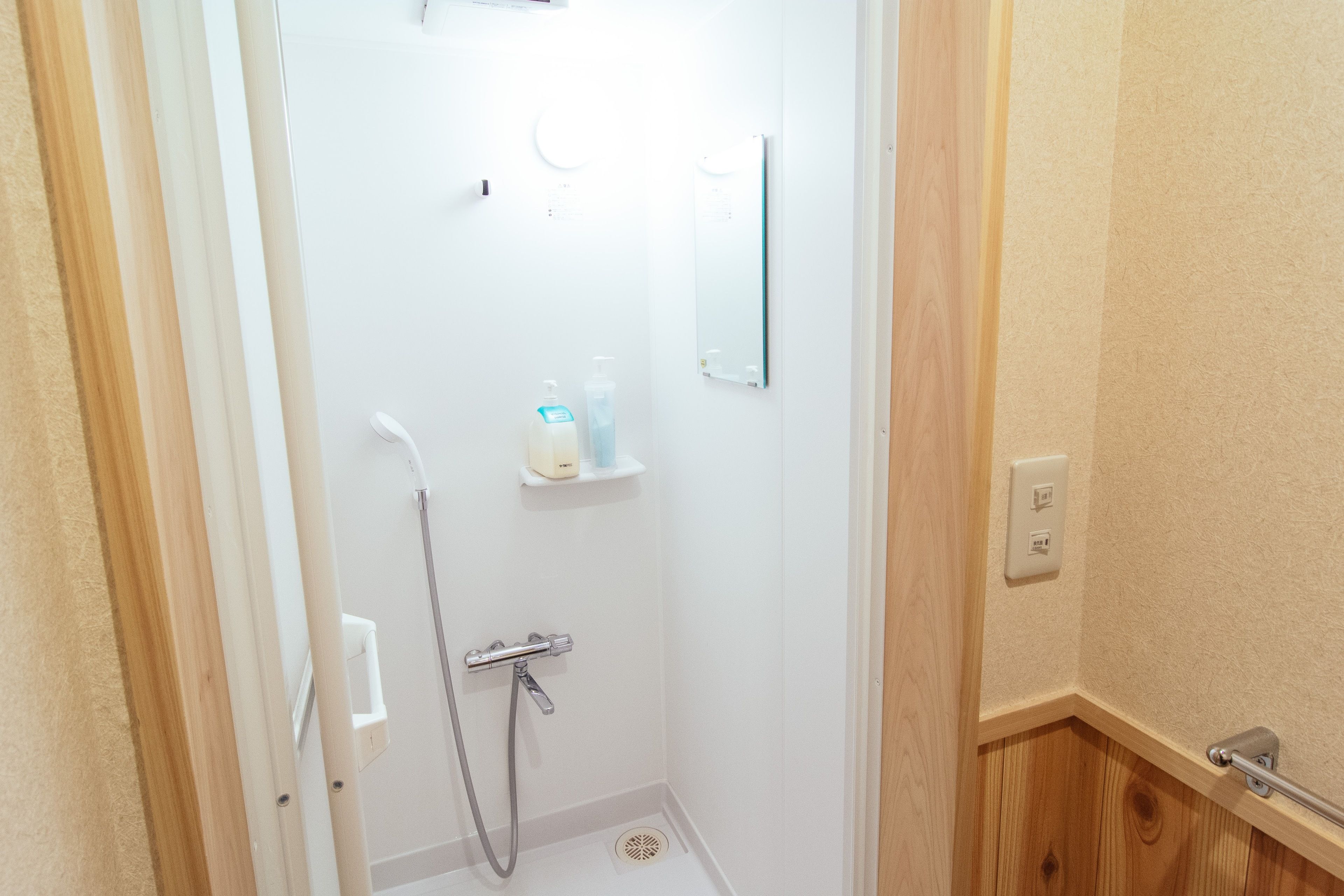 A small, white bathroom with a shower, a toilet, and a mirror.