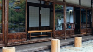 A traditional wooden building with large sliding doors, a wooden bench outside, and a stone-paved ground. - Koyasan Syukubo Kumagaiji (Koya)