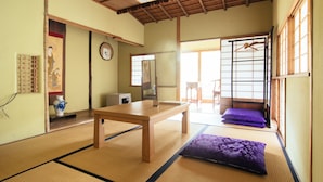 A traditional Japanese room with tatami flooring, a wooden table, a sofa with purple cushions, and sliding doors. - Koyasan Syukubo Kumagaiji (Koya)