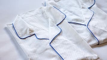 Two neatly folded white pillows with blue piping, placed on a white surface.