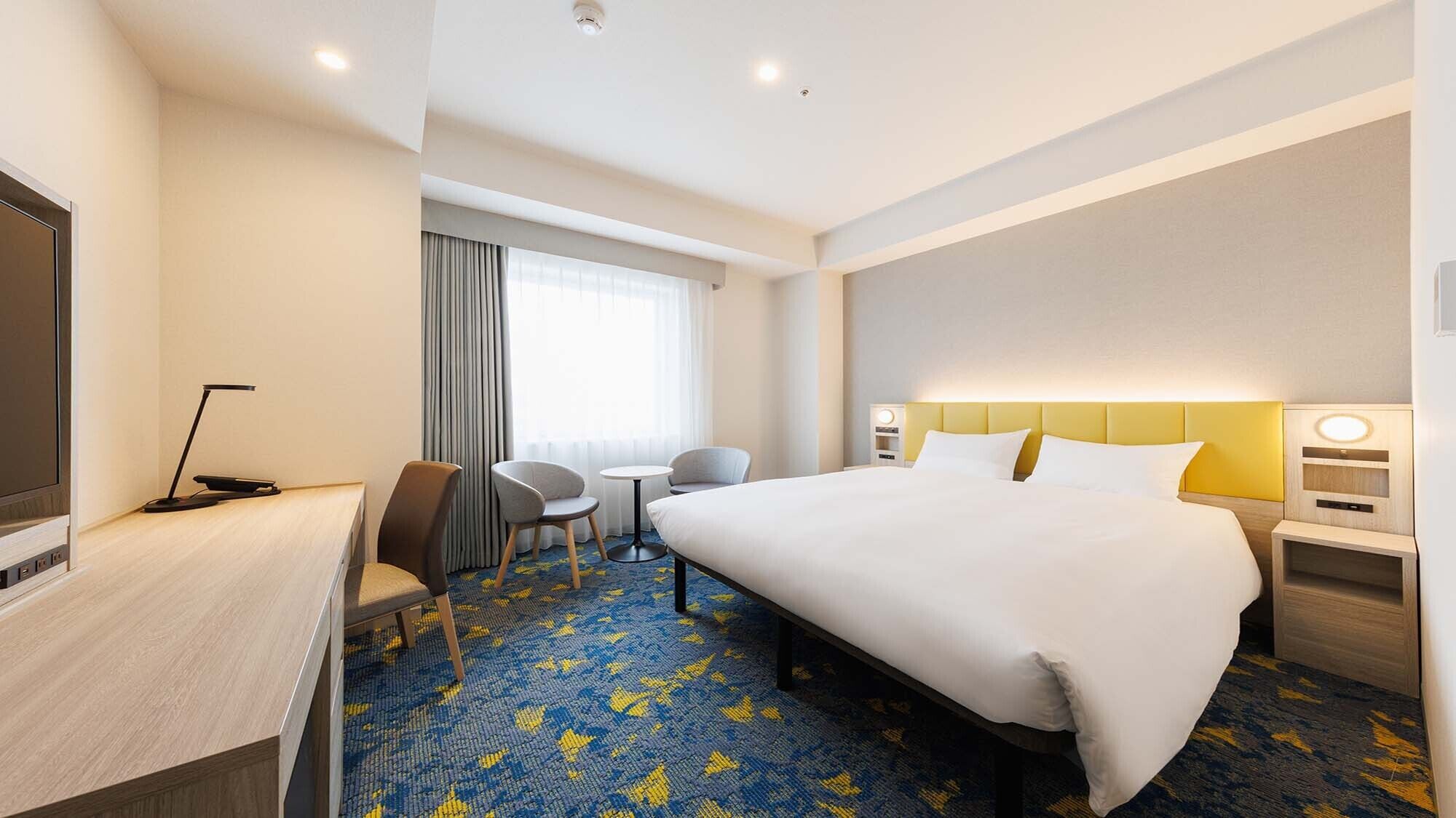 Een hotelkamer met een bed, bureau, stoel en een tafeltje.