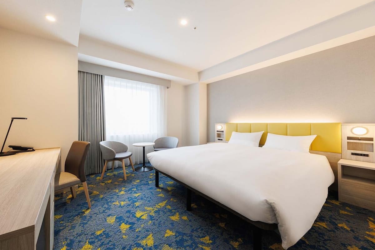 Ein Hotelzimmer mit Bett, Schreibtisch, Stuhl und einem kleinen Tisch.
