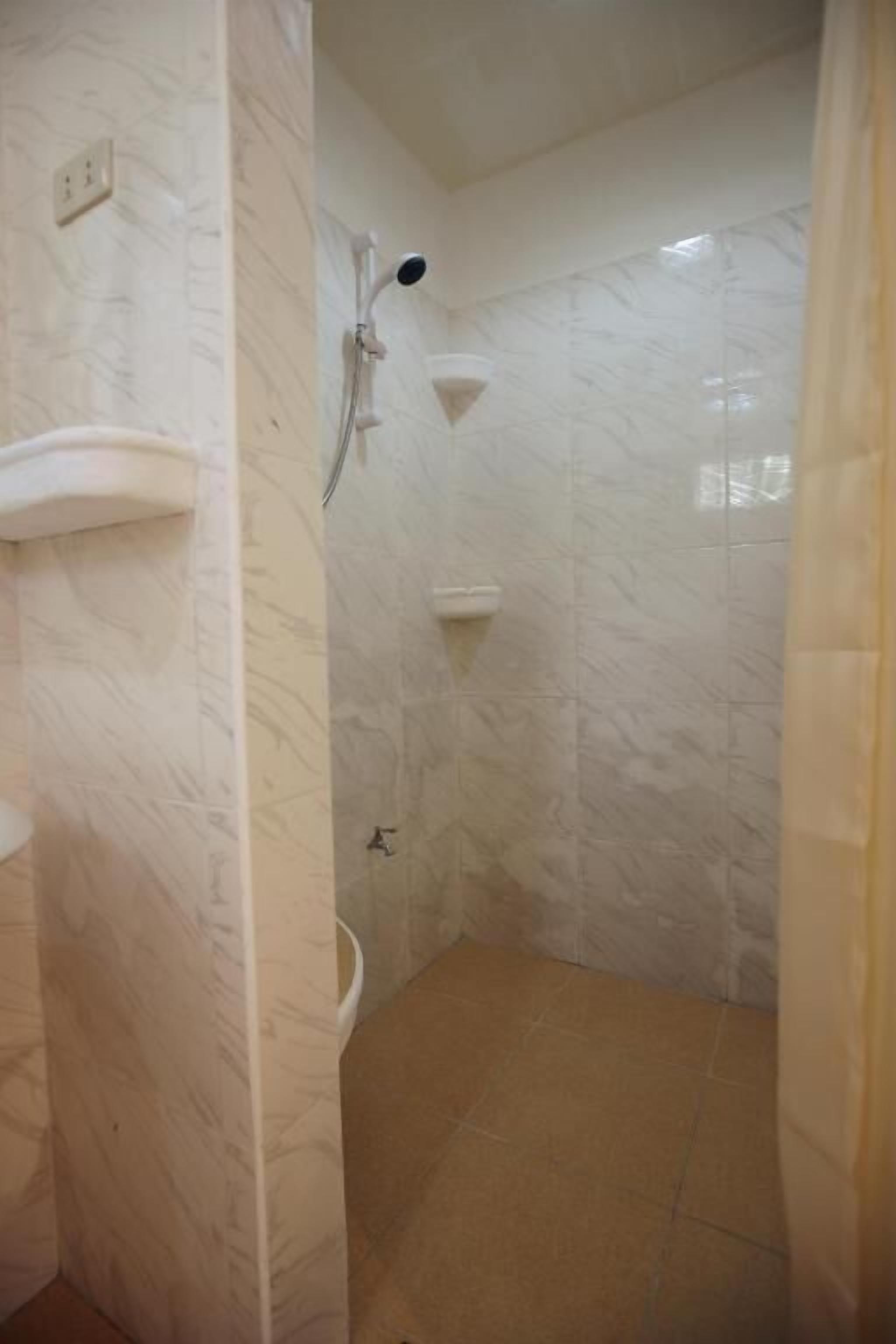 A bathroom with a marble wall, a sink, and a shower.