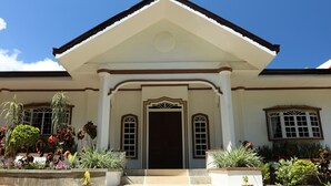 A building with a central entrance, flanked by two windows with decorative frames, and a triangular pediment above.