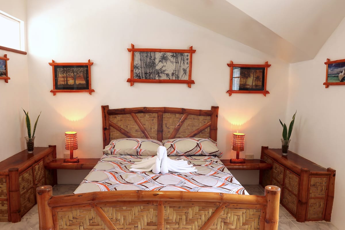 A neatly arranged bedroom with a large bed, wooden headboard, and bedside tables with lamps.