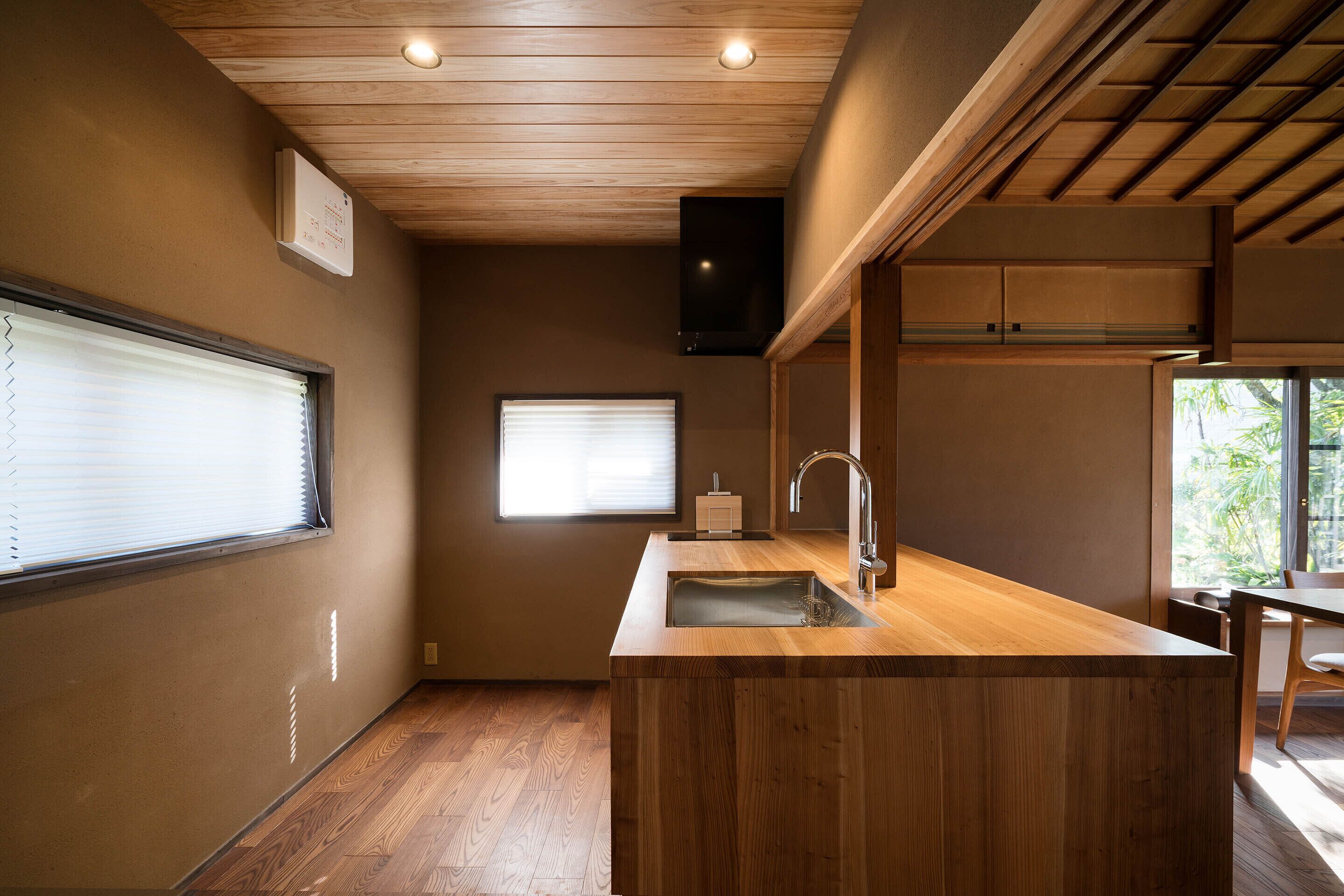A compact kitchen with wooden countertops, a built-in sink, and a ceiling fan.