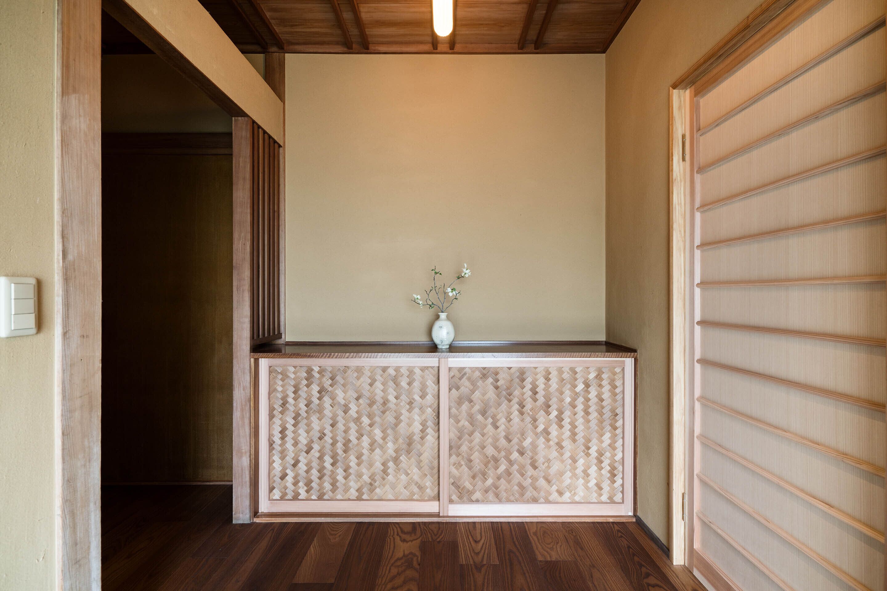 A room with a wooden floor, a beige wall, and a sliding door with horizontal slats.
