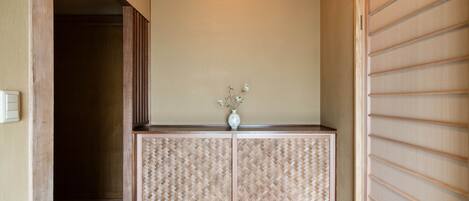 A room with a wooden floor, a beige wall, and a sliding door with horizontal slats.