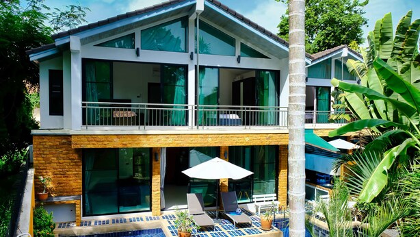 A two-story building with a balcony, a swimming pool, and lounge chairs. - 4poolvillas (Pattaya)