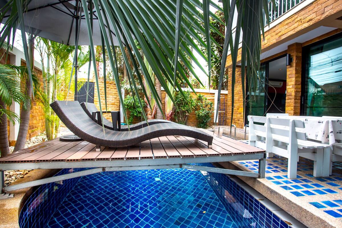A poolside area with a lounge chair, a small table, and a bench.