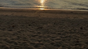 A beach with the sun setting over the water, creating a reflection on the surface. - 4poolvillas (Pattaya)