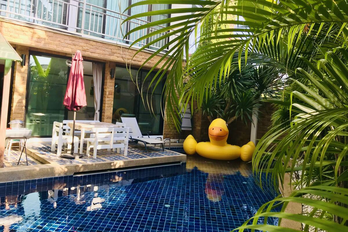 A pool area with lounge chairs and a yellow inflatable duck.