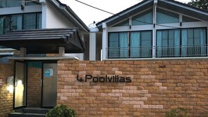 A building with a sign reading "4 Poolvillas" and a brick wall. - 4poolvillas (Pattaya)
