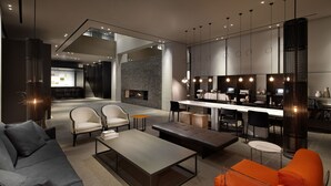 Un espacio moderno para relajarse con sofá, mesa de centro y sillas color naranja. Hay chimenea y una zona de cocina con mostrador y sillas.