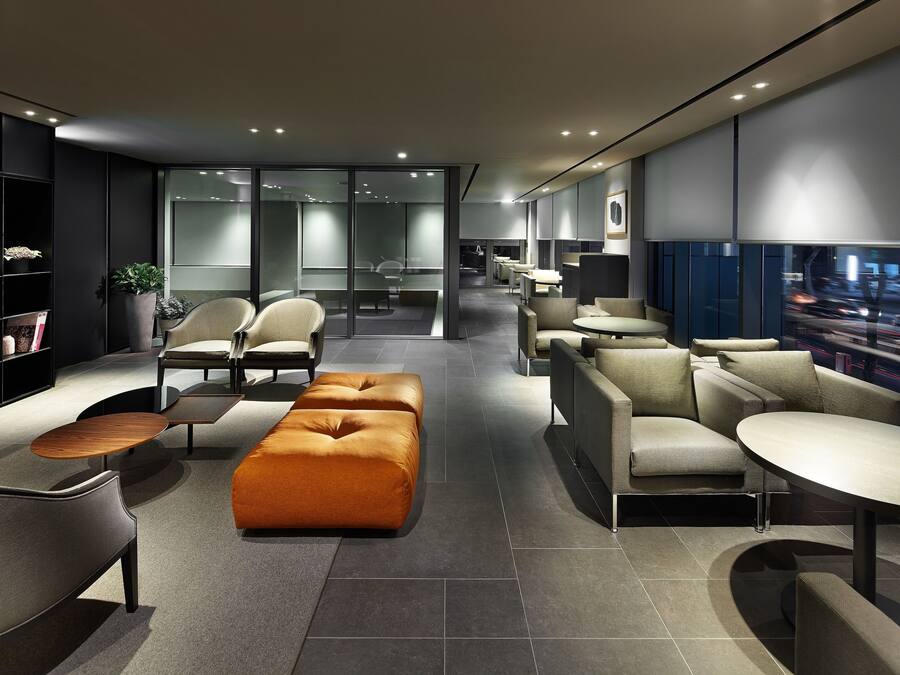 A modern lounge area with seating arrangements, a coffee table, and a bookshelf.