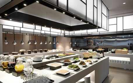 A modern buffet setup with various food stations and glassware.