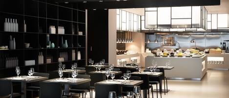 Un restaurante moderno con varias mesas, sillas y una zona de cocina al fondo.