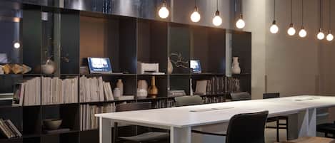 A modern conference room with a long table, black chairs, and a bookshelf filled with books and decorative items.