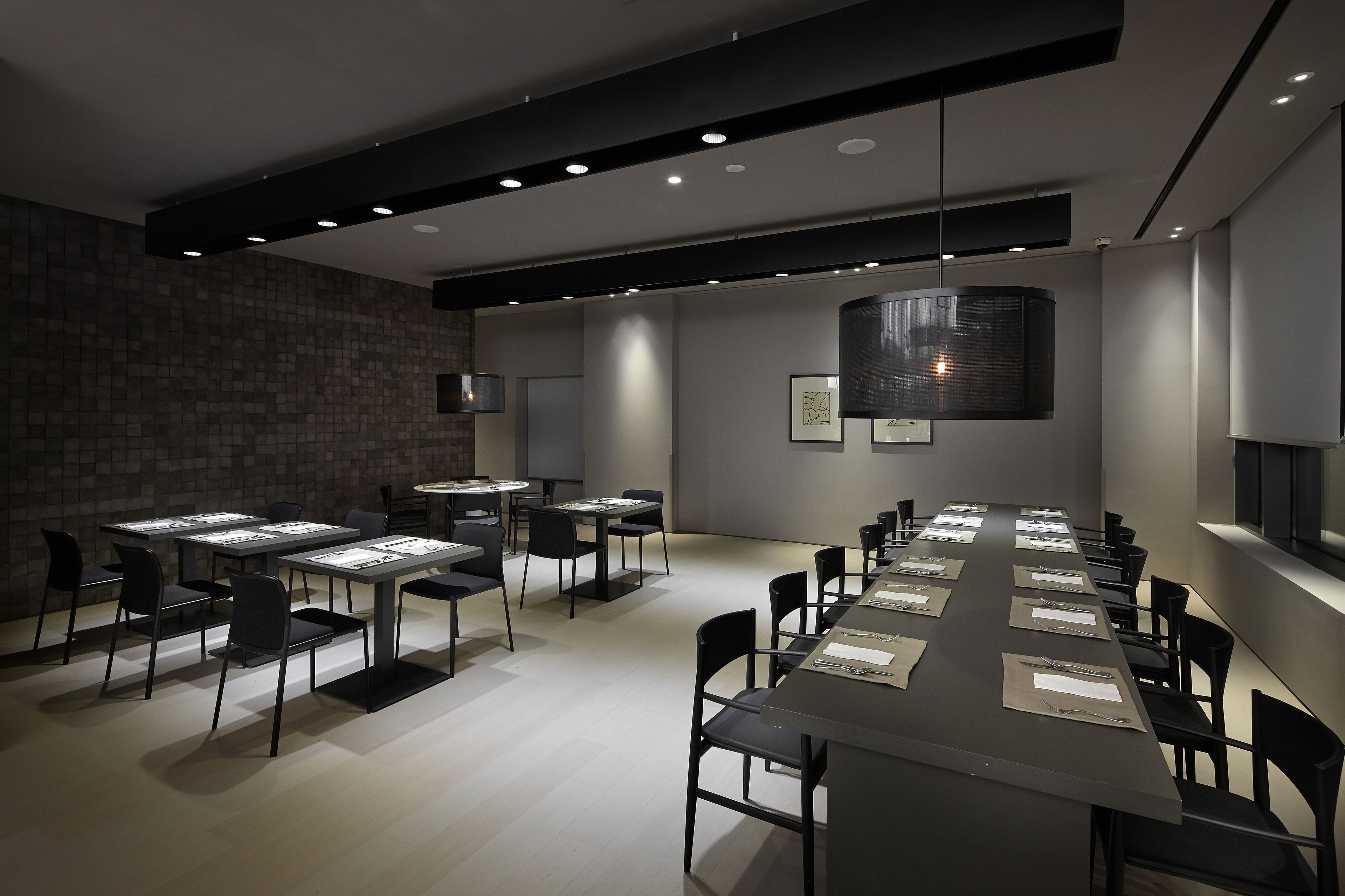 A modern conference room with a long table, multiple chairs, and recessed lighting.