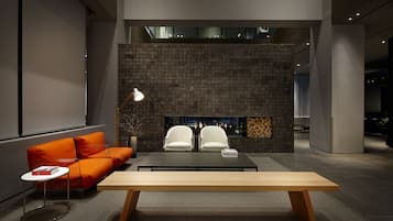 Un área de estar moderna con un sofá, dos sillones, una mesa de centro y una chimenea.