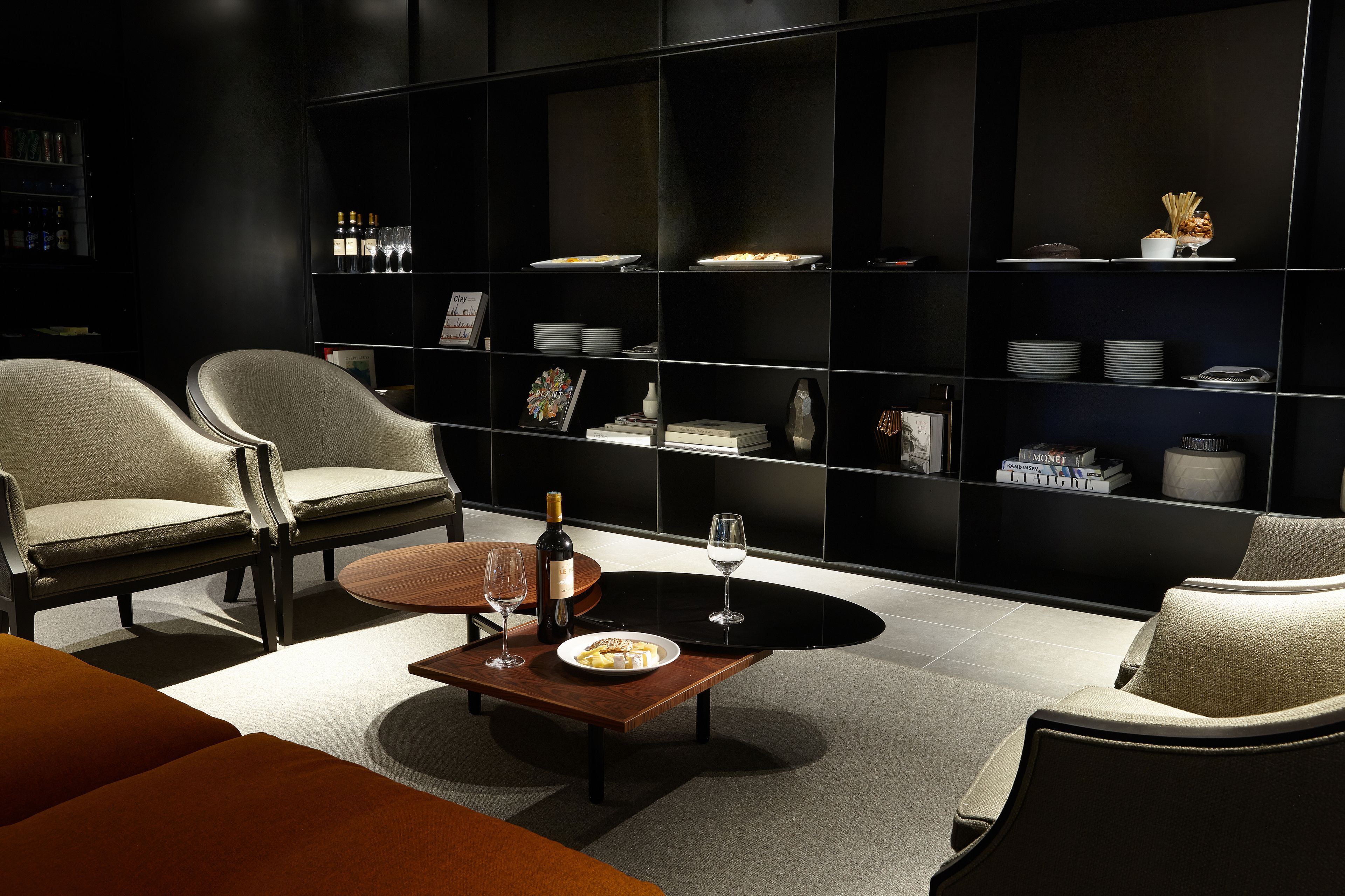 Una sala de estar moderna con un mueble de entretenimiento negro, dos sillones, una mesa de centro y una botella de vino.